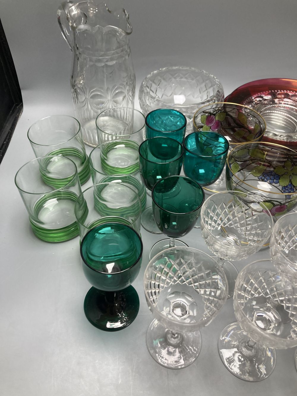 A collection of clear and coloured glassware, including four green bowled wines, vine etched cranberry tumblers, dessert bowls etc.